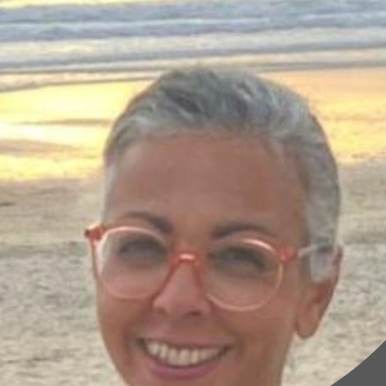 Portrait de la praticienne, souriante, sur une plage au coucher du soleil